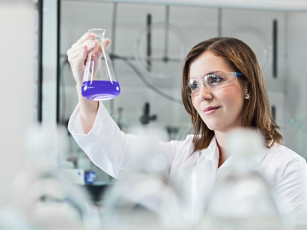 一位女科学家穿着白大褂，戴着护目镜，正在实验室里做实验.