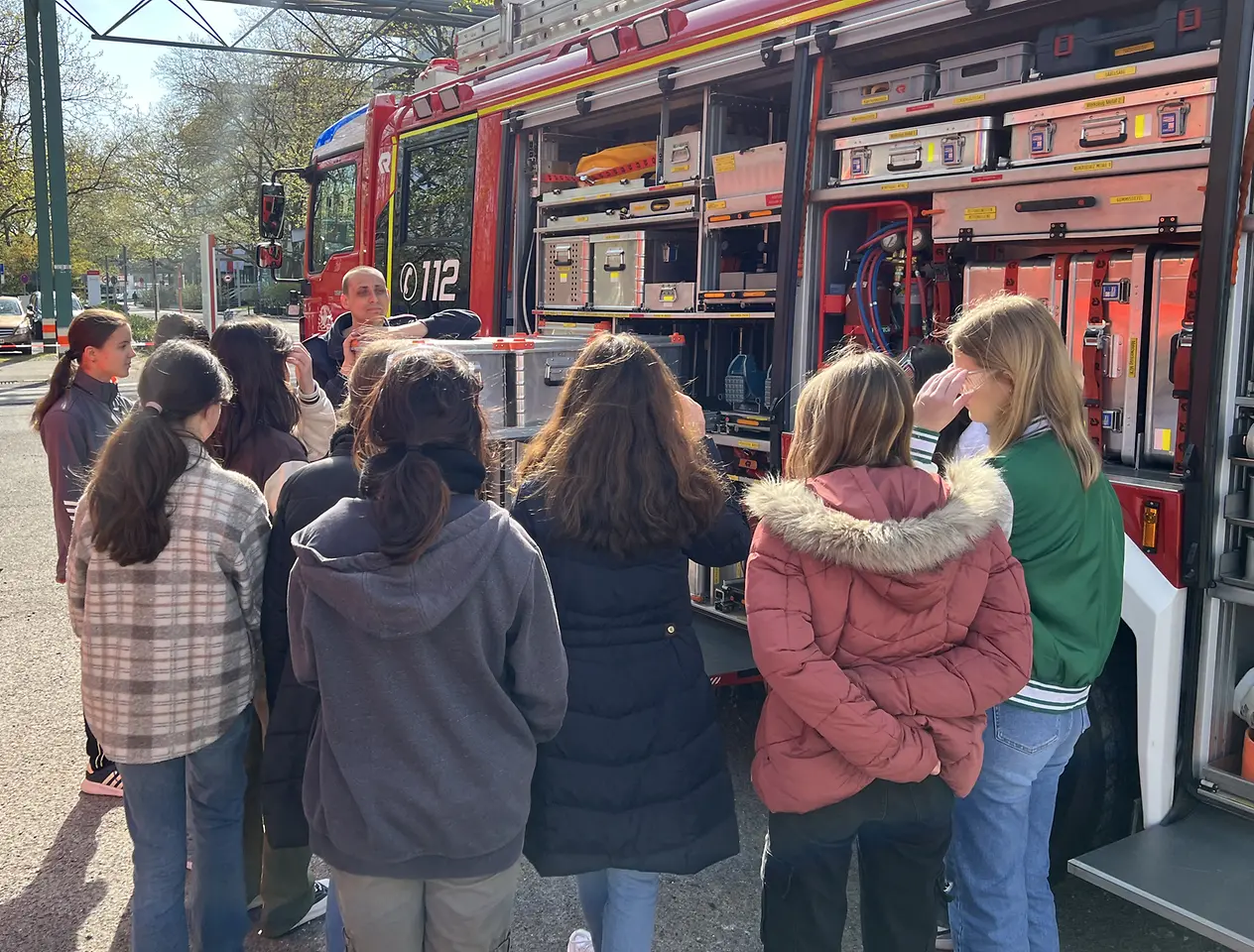 Mehrere Schülerinnen stehen vor einem geöffneten Feuerwehrfahrzeug.