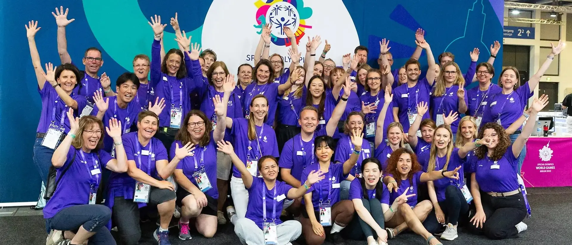 60 ehrenamtliche Helfer:innen von Henkel jubeln bei den Special Olympics auf einem Gruppenfoto.