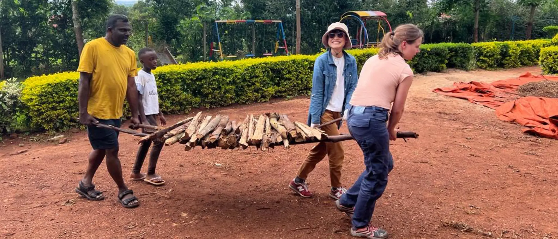 Die ehrenamtlichen Helfer unterstützen die Einheimischen in Uganda beim Tragen von Holz.