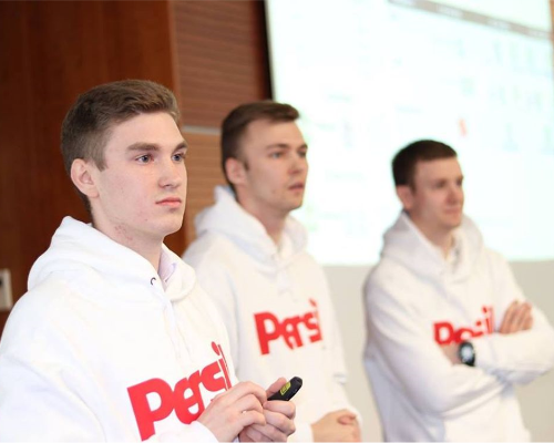 Three Henkel employees wearing a Persil sweater and holding a presentation.