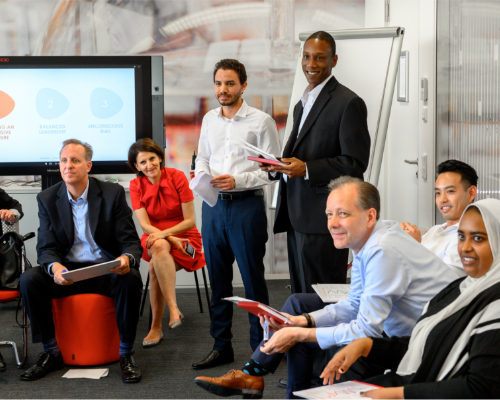 Ein vielfältiges Henkel-Team sitzt bei einem Workshop zusammen und schaut zum Redner