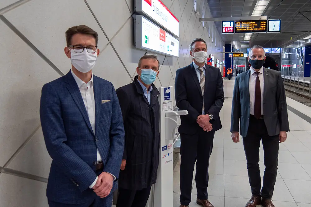 Henkel-Standortleiter Dr. Daniel Kleine, Oberbürgermeister Thomas Geisel, Leiter Standortlogistik BASF in Düsseldorf Dr. Uwe Hömmerich und Vorstandsvorsitzender der Rheinbahn Klaus Klar (vlnr.) bei der Installation eines Desinfektionsmittelspenders an einer U-Bahn Haltestelle der Rheinbahn.