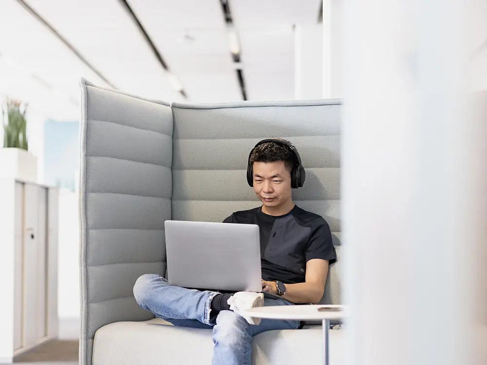 Ein Henkel-Mitarbeiter mit Kopfhörern arbeitet konzentriert an seinem Laptop. 