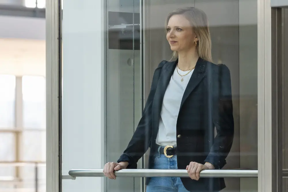 Eine Frau schaut aus der Glasfront eines Bürogebäudes