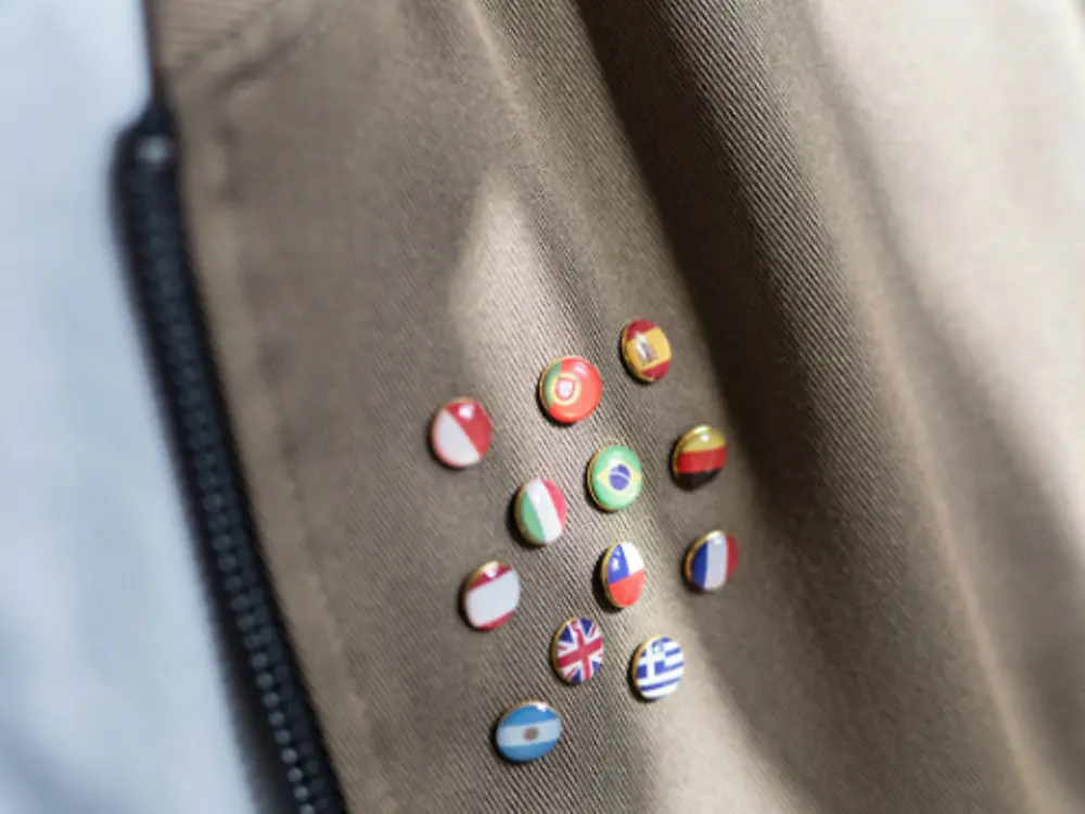 Anstecknadeln verschiedener Nationen an einer Jacke.