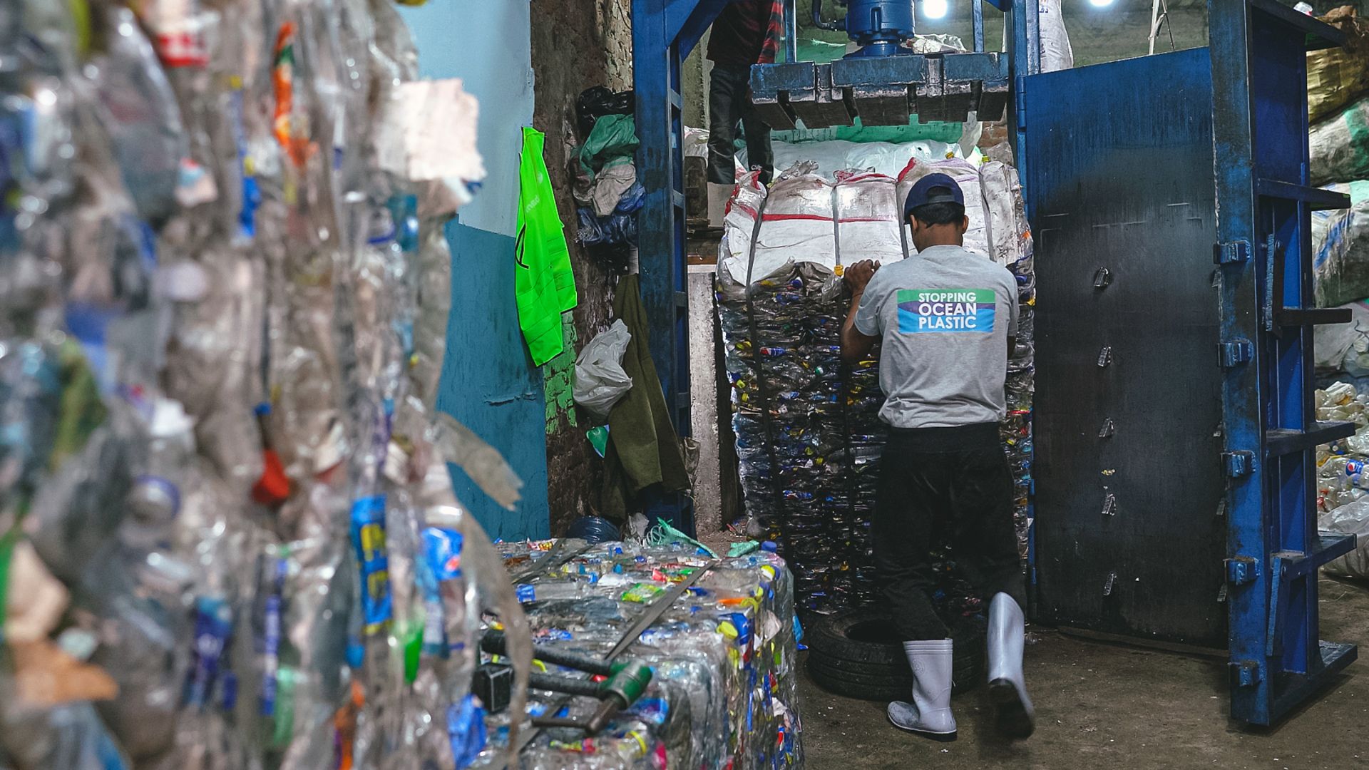 Ein Mitarbeiter von Plastic Bank zieht einen Block gepressten Plastikmülls aus der Anlage.