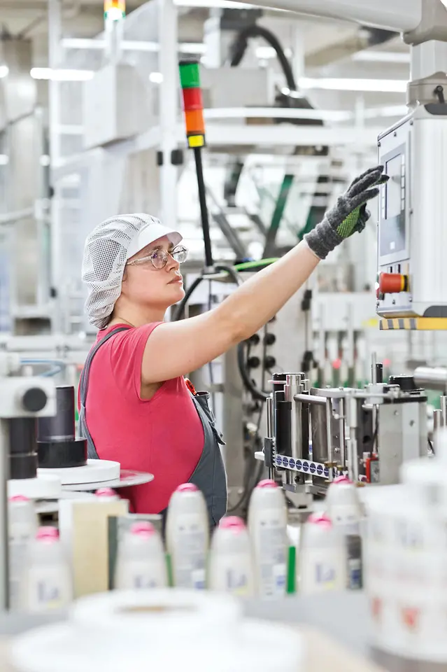 Eine Mitarbeiterin in der Beauty Care-Produktion bedient den Touchscreen einer Maschine.