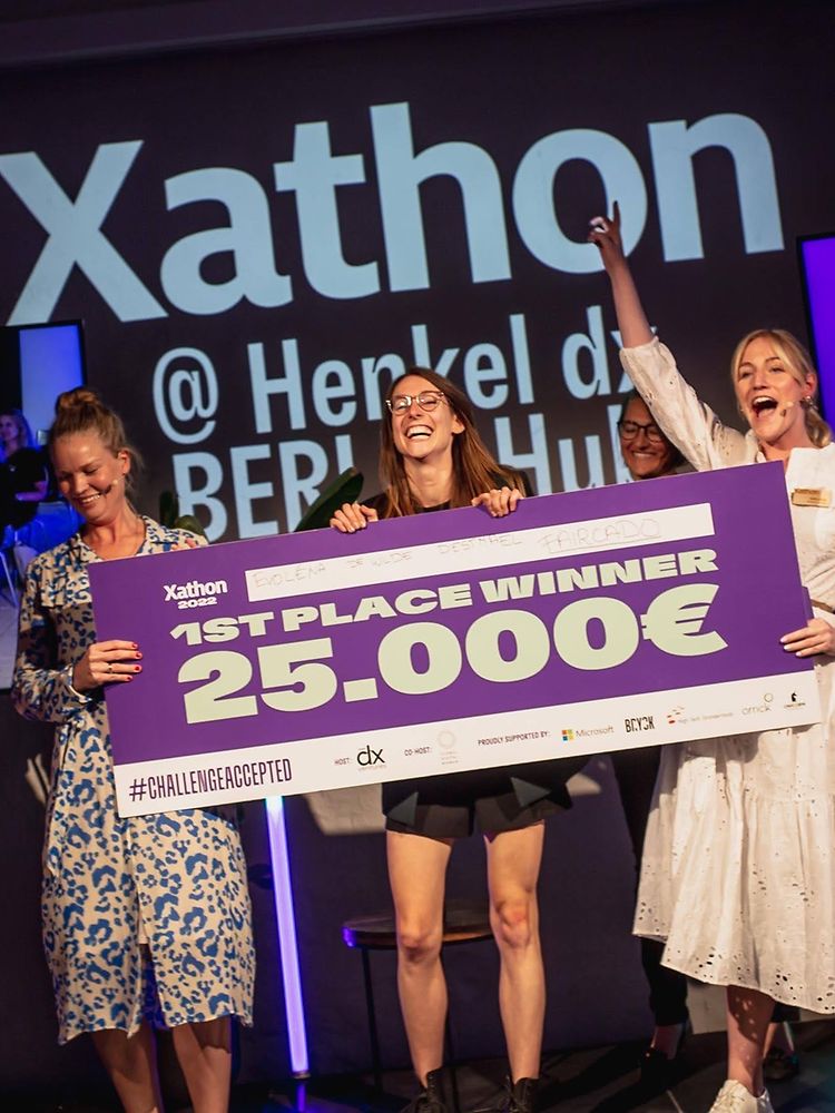 Die Gewinnerinnen des Henkel Xathons stehen auf einer Bühne und halten den Preis für den ersten Platz.