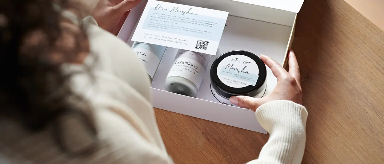 Eine Frau öffnet ein Paket mit personalisierten Produkten von SalonLab&Me