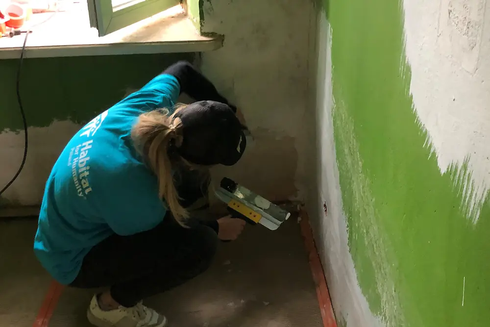 Eine Frau verspachtelt eine Wand.