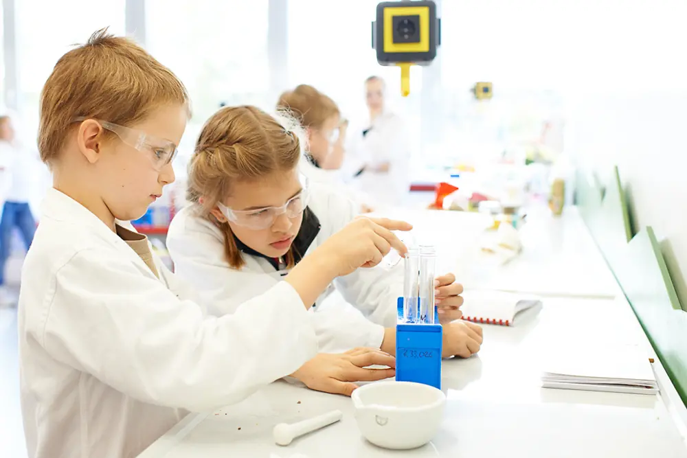 Ein Junge und ein Mädchen schauen konzentriert auf ihr Forscherwelt-Experiment.