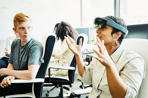 Zwei Mitarbeiter:innen nehmen an einem Training teil, in dem sie eine VR-Brille ausprobieren. 