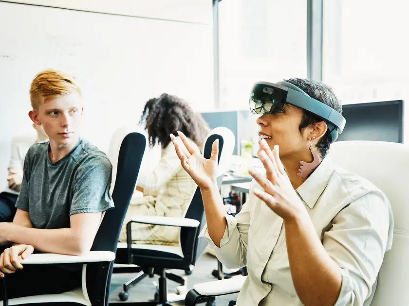 Zwei Mitarbeiter:innen nehmen an einem Training teil, in dem sie eine VR-Brille ausprobieren. 