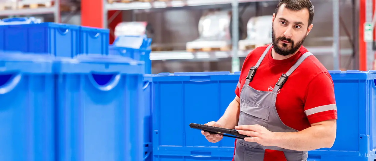 Ein Mitarbeiter steht in der Produktionsanlage und überprüft, ob die Prozesse wie gewünscht verlaufen.
