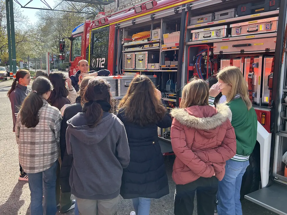 Mehrere Schülerinnen stehen vor einem geöffneten Feuerwehrfahrzeug.