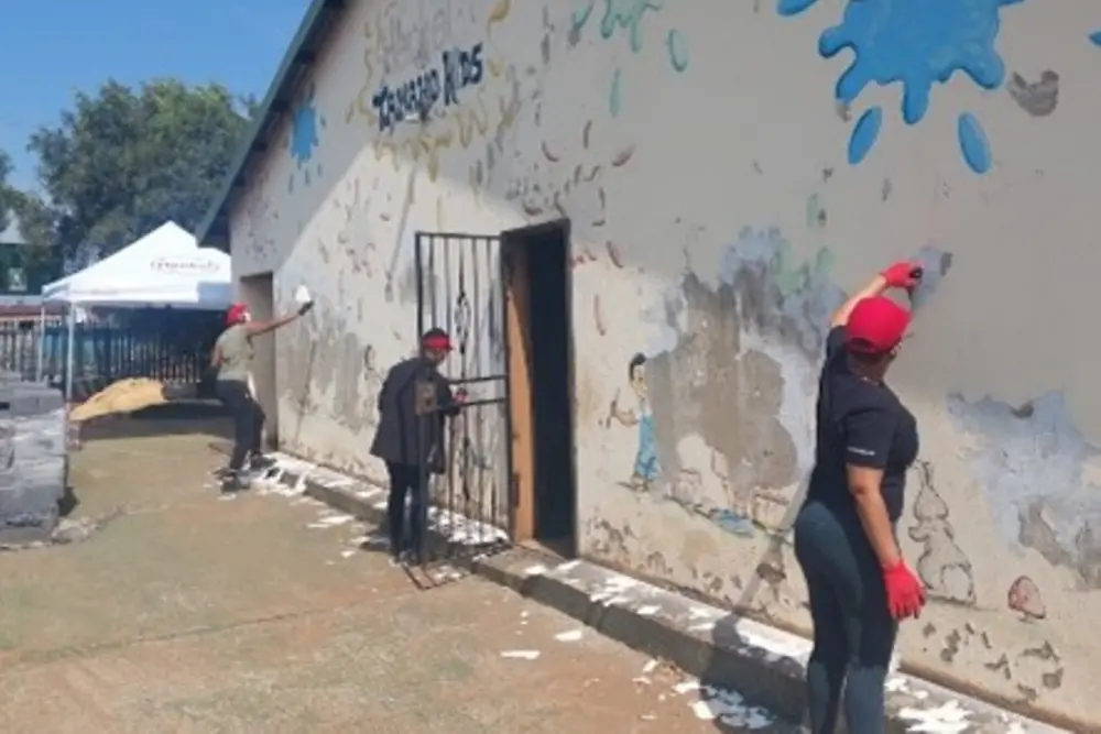 Freiwillige von Henkel streichen die Wand eines Klassenzimmers.