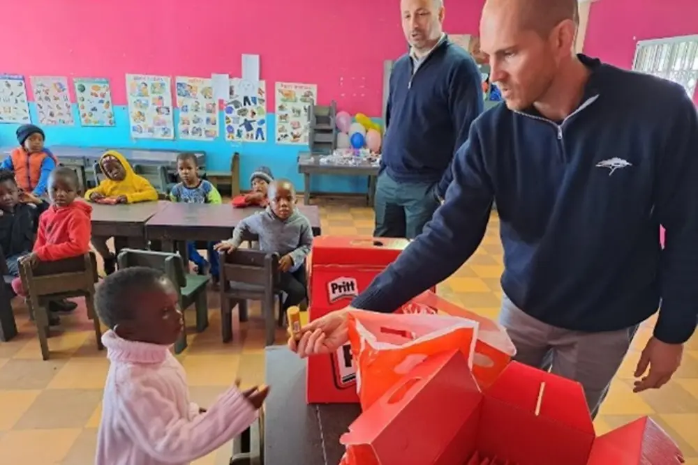 Ein Freiwilliger von Henkel übergibt einem Kind einen Pritt Stift.