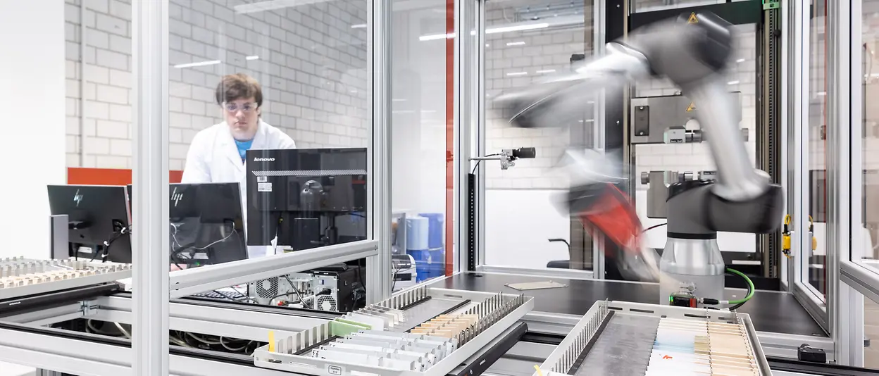 In einem automatisierten Labor arbeitet ein Roboterarm an Klebstofftechnologien.