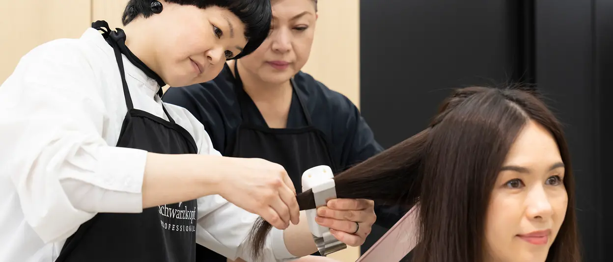 Zwei Haarpflegeexpertinnen behandeln das Haar einer Kundin mit dem SalonLab Smart Analyzer.