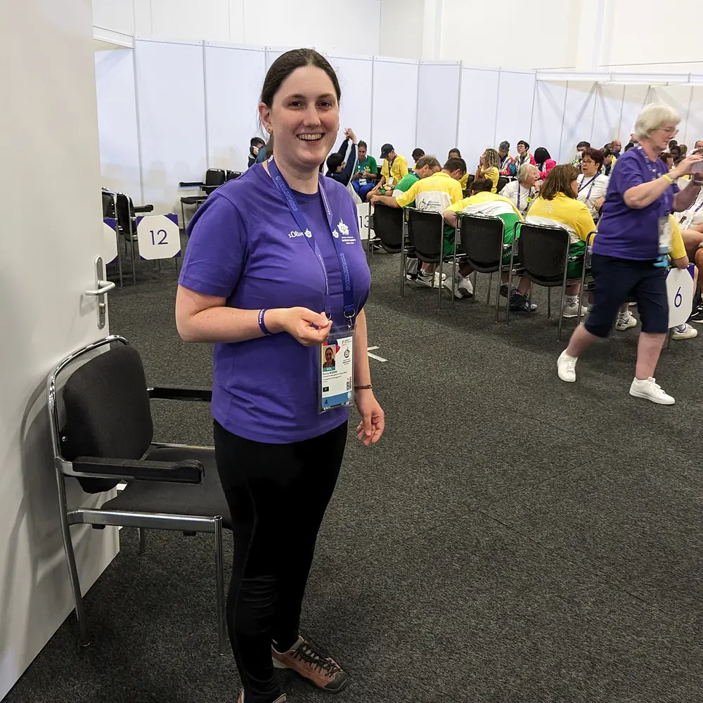 Katrin steht in einem der Vorbereitungsräume für die Special Olympics Athlet:innen und lächelt in die Kamera.