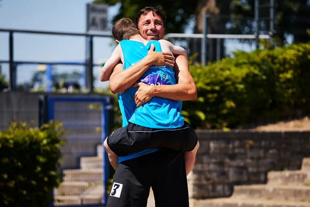 Ein Mitarbeiter von Henkel umarmt lachend einen Athleten bei den Special Olympics.