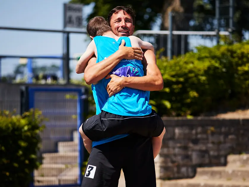 Ein Mitarbeiter von Henkel umarmt lachend einen Athleten bei den Special Olympics.
