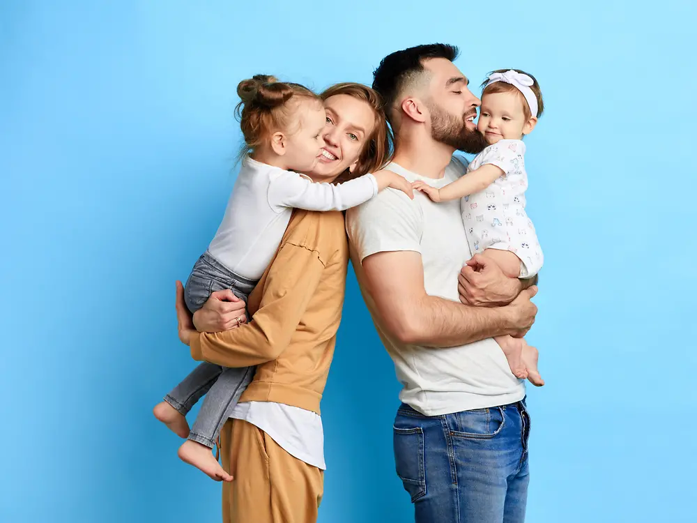 Eine Familie von 4 steht vor einem blauen Hintergrund.
