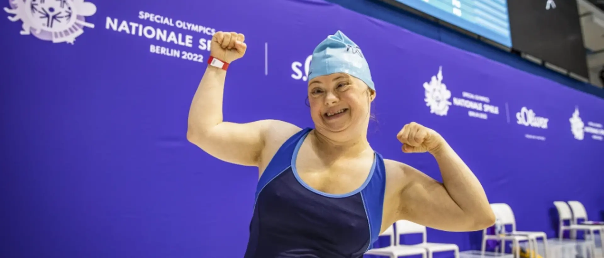 Eine Schwimmerin, die bei den Special Olympic teilnimmt, schaut jubelnd in die Kamera.