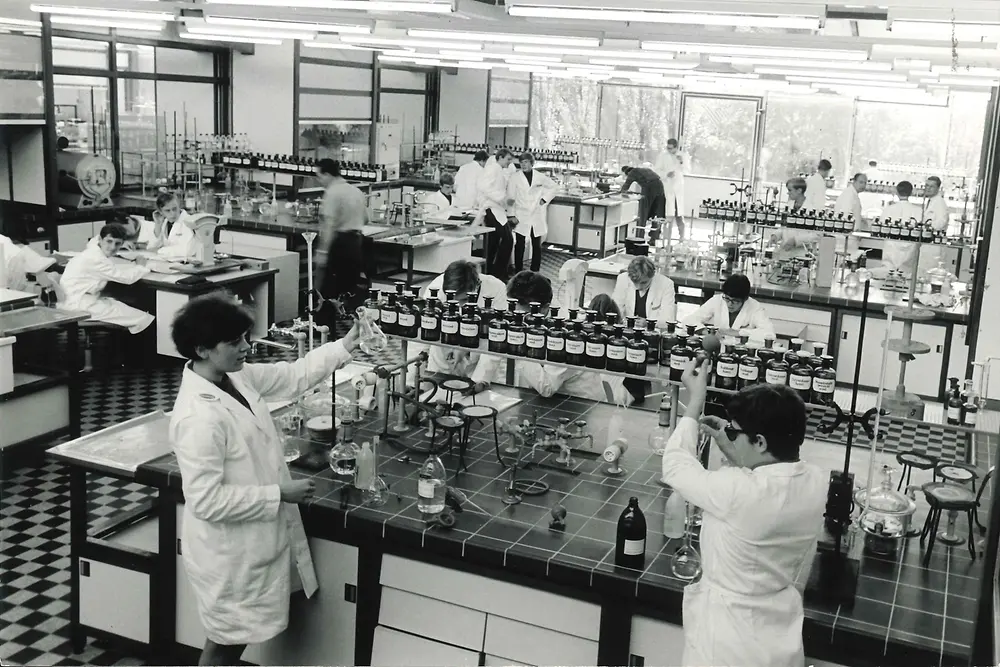 Chemielaborant:innen mit weißen Kitteln bei der Arbeit im Chemielaboratorium. 