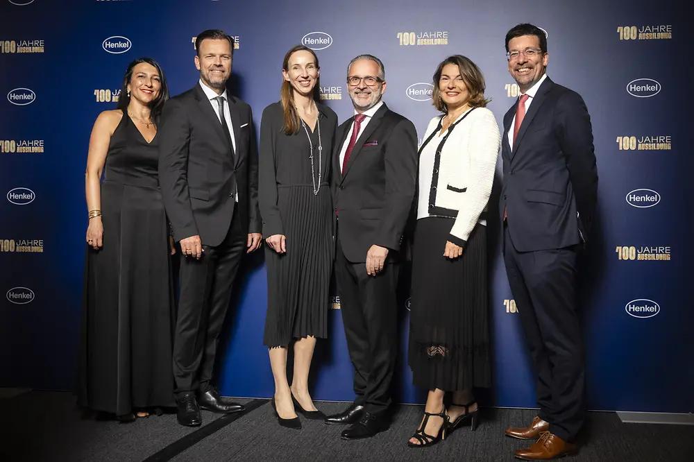 Funda Mutlu, Leiterin der Ausbildung bei Henkel, Oliver Wilhelms, Personalleiter von Henkel Deutschland und Schweiz, Dr. Simone Bagel-Trah, Vorsitzende des Aufsichtsrats und Gesellschafterausschusses, Carsten Knobel, CEO von Henkel, Sylvie Nicol, Mitglied des Vorstands, zuständig für Personal, Infrastruktur und Nachhaltigkeit und Mark Dorn, Mitglied des Vorstands, zuständig für den Unternehmensbereich Adhesive Technologies stehen vor einer Fotowand. 