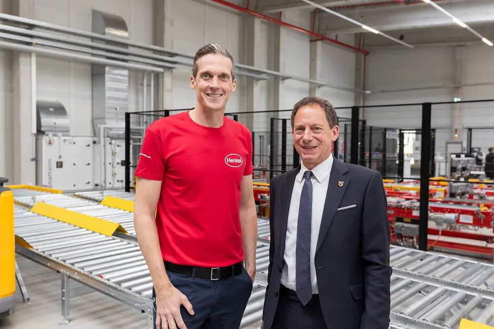Carsten Vagt, Werkleiter Henkel Wassertrüdingen und Stefan Ultsch, Bürgermeister der stehen vor dem Förderband zum Hochregallager.