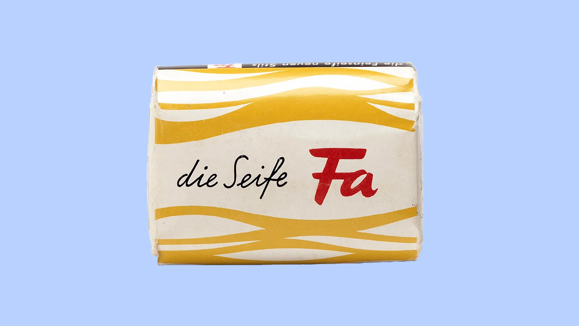 Ein Päckchen Fa-Seife aus dem Jahr 1954. Die Verpackung ist weiß mit gelben wellenförmigen Linien, die Fäden repräsentieren sollen. Mittig die Aufschrift „die Seife Fa“.