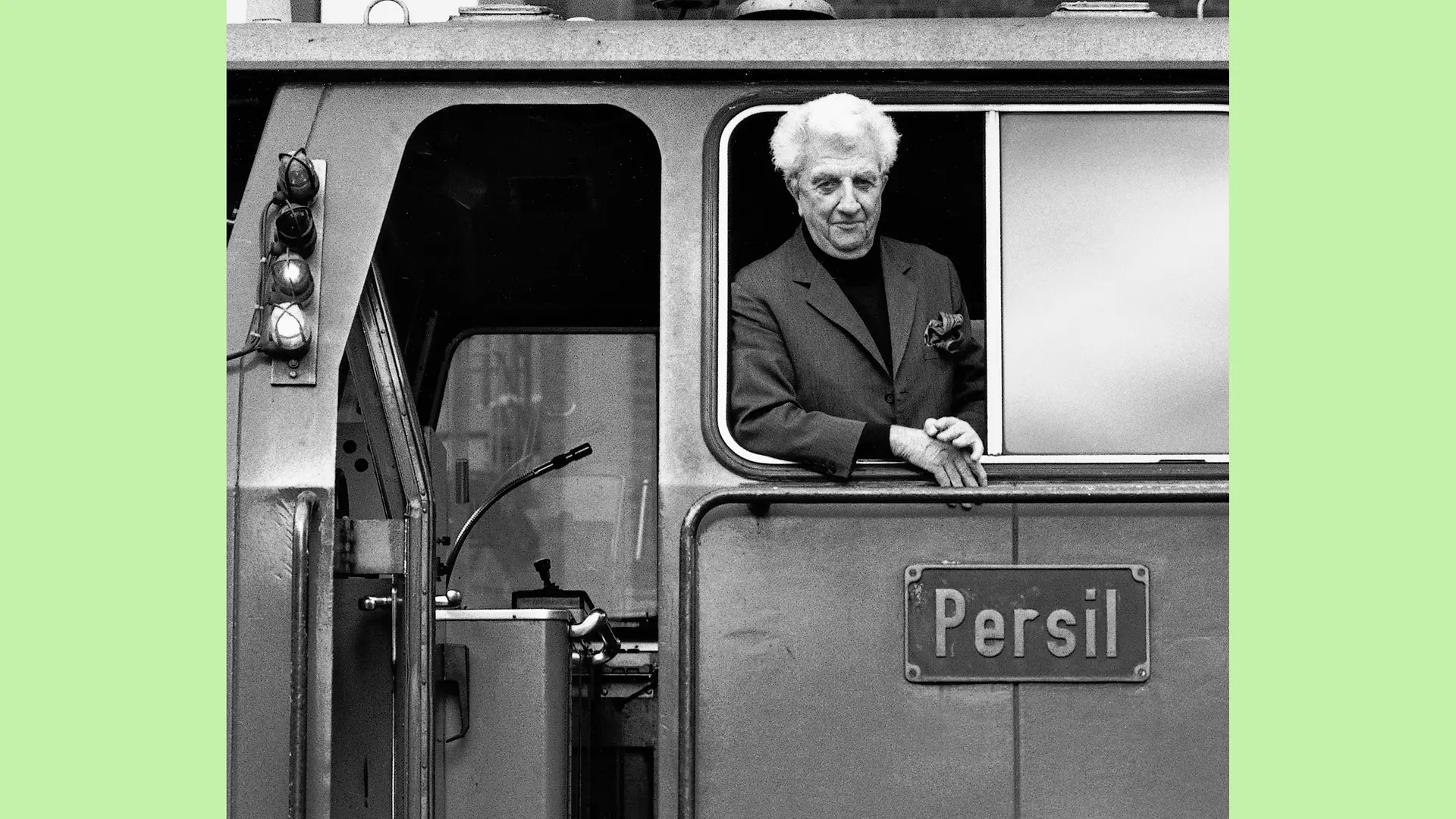 Dr. Konrad Henkel lehnt sich lächelnd aus dem Seitenfenster des Führerhäuschens der Lokomotive Persil.
