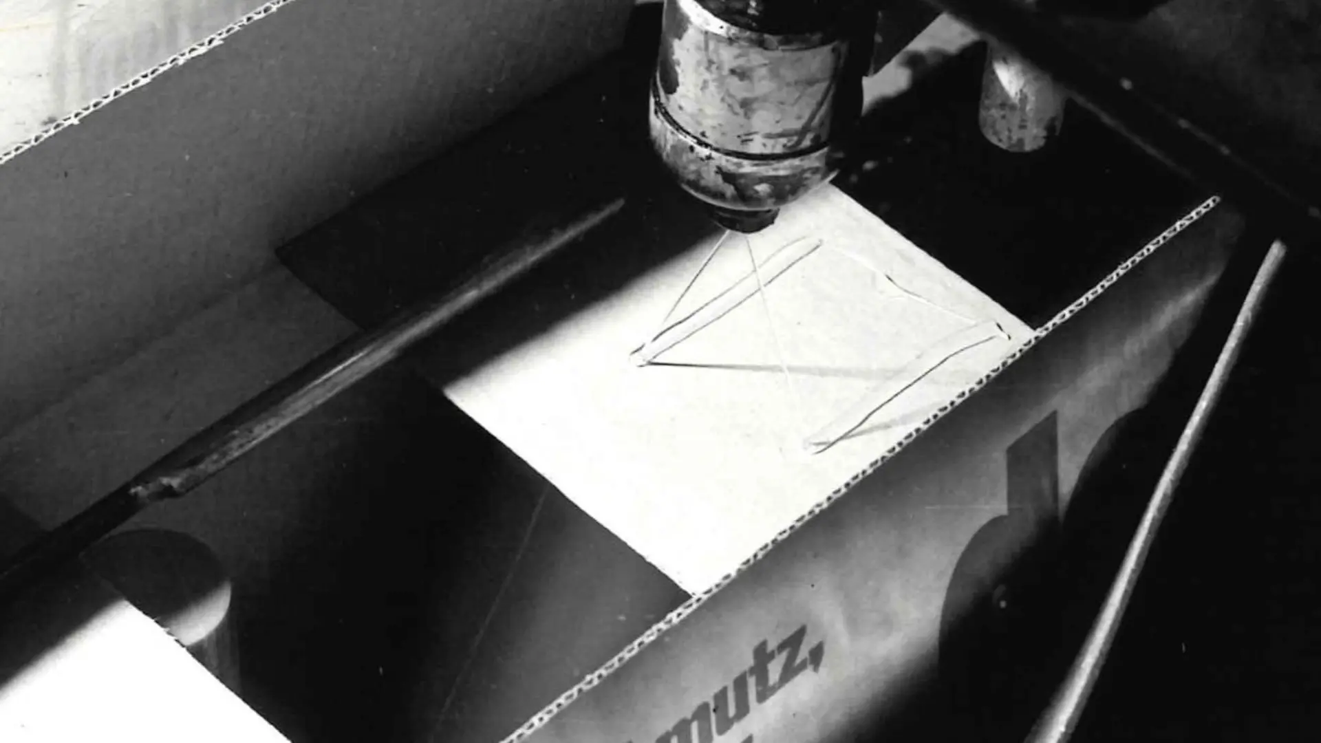 Technomelt-Schmelzklebstoff wird von einem Sprühkopf auf einen Karton aufgetragen, um diesen zu verschließen.