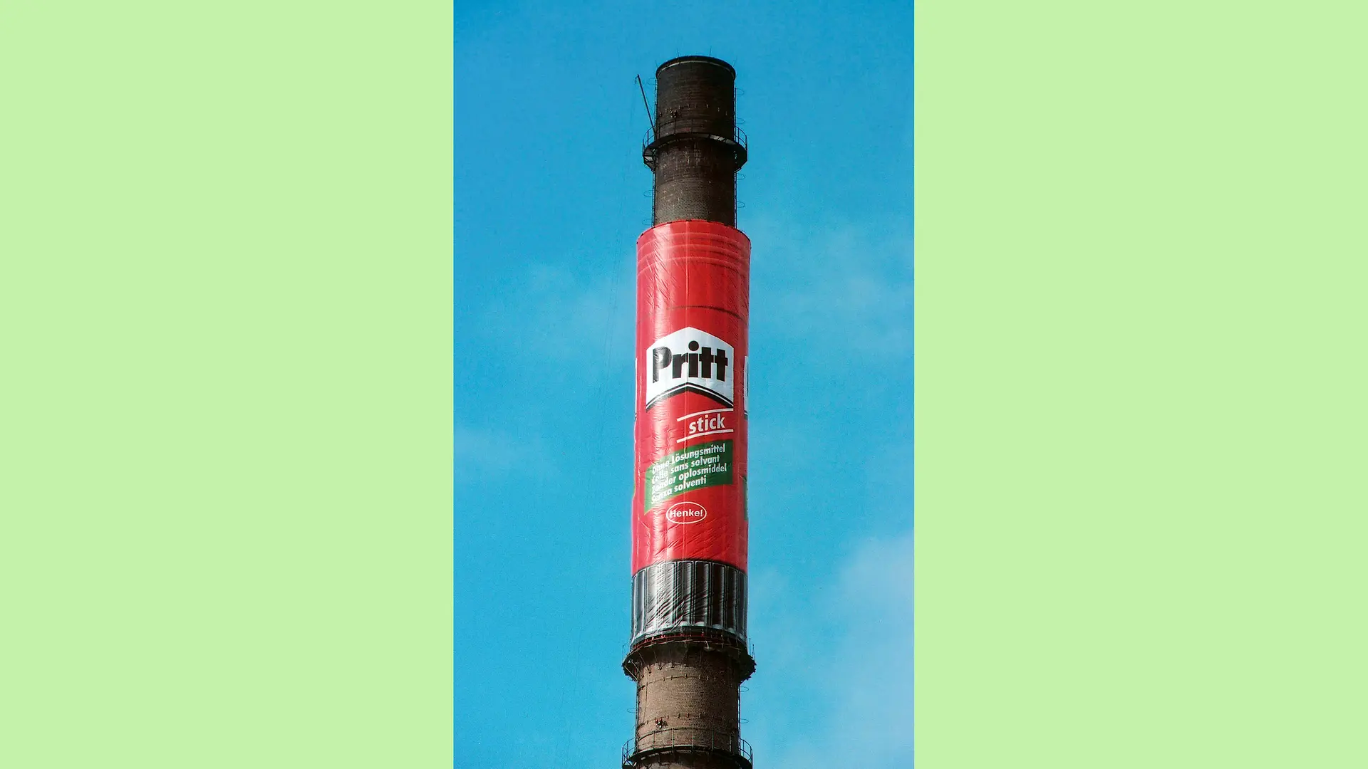 Foto eines Schornsteins auf dem Henkel Werksgelände in Düsseldorf-Holthausen, der mittig mit einer Plane in Form eines riesigen Pritt-Stifts umhüllt wurde.