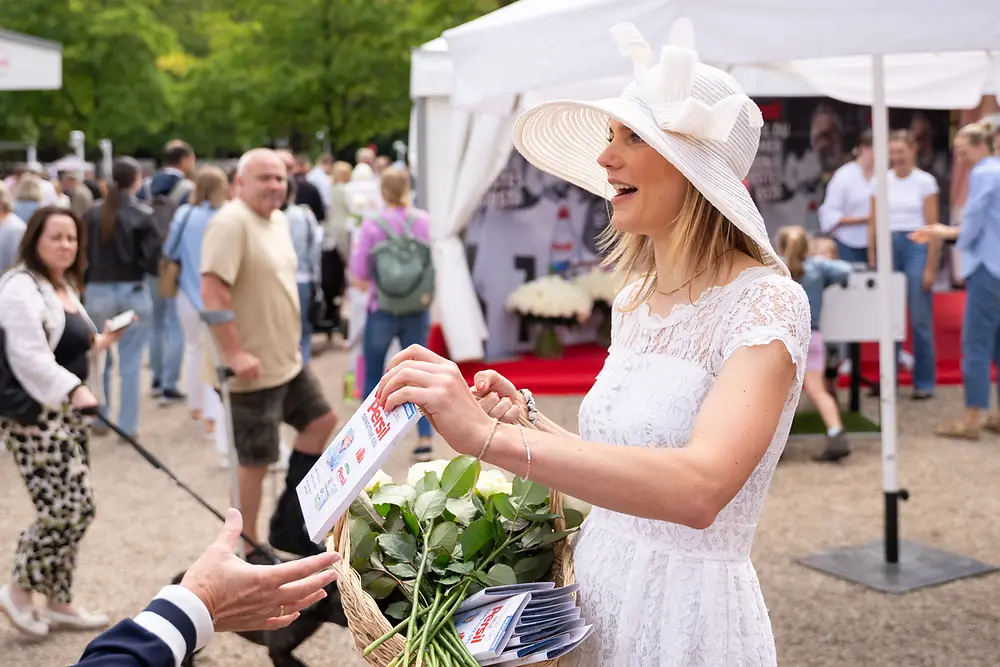 
Die weiße Dame von Persil verteilte Rosen an Besucher:innen.