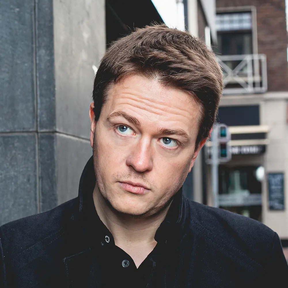 Johann Hari, ein britischer Journalist und Autor von „Abgelenkt“, steht im Freien in der Nähe eines Gebäudes.