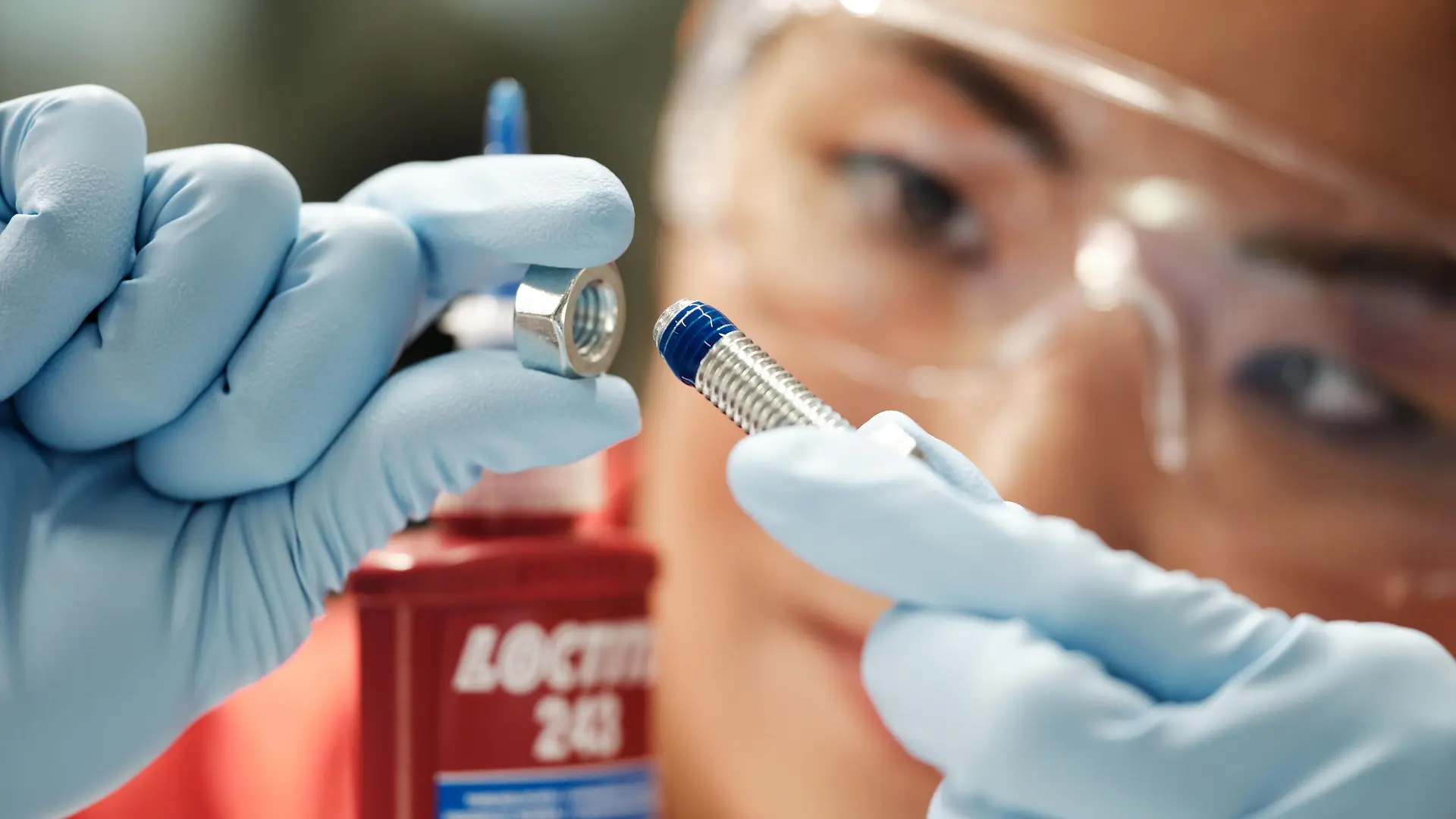 Nahaufnahme einer Person, die Loctite-Klebstoff auf eine Schraube aufträgt – als Symbol für Präzision und Innovation im Geschäft mit Industrieklebstoffen von Henkel.