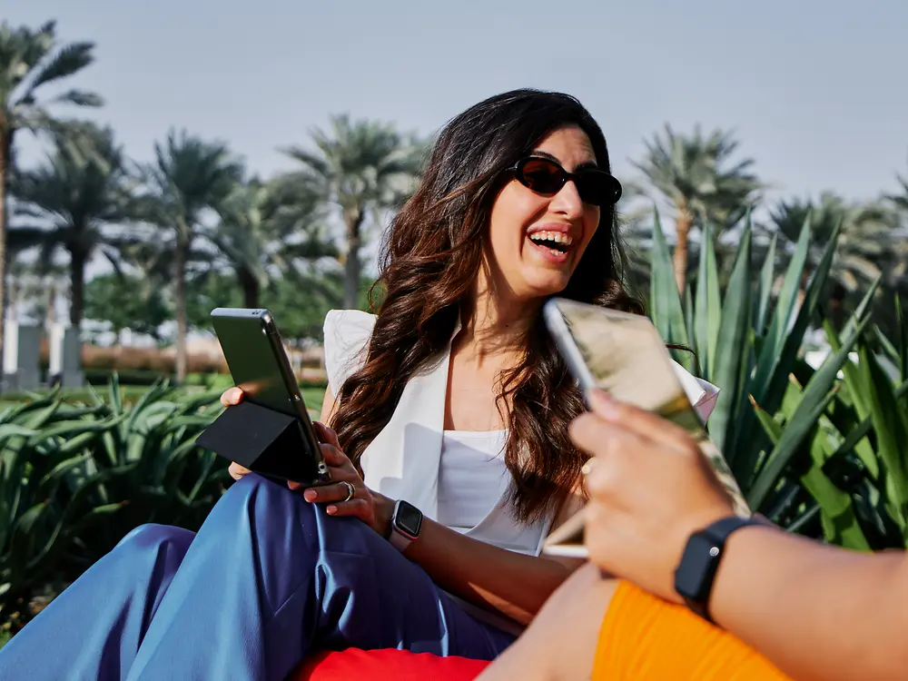 Eine Frau arbeitet an einem Laptop im Freien in einem sonnigen Park – als Ausdruck der flexiblen Arbeitsmöglichkeiten und modernen Arbeitskultur bei Henkel.