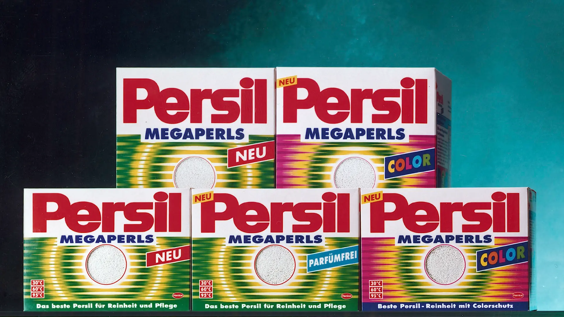 Eine Reihe von Persil‑Megaperls‑Waschmittelpackungen ist abgebildet. Die Packungen zeigen verschiedene Varianten, darunter Standard‑ und Color‑Versionen, und tragen jeweils das Persil‑Logo, eine auffällige Typografie sowie das charakteristische Perlen‑Design des Waschmittels.