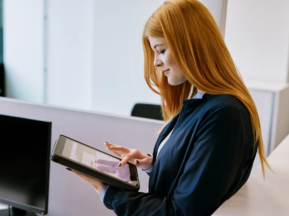 Eine Frau, die im Büro den Bildschirm eines Tablets berührt