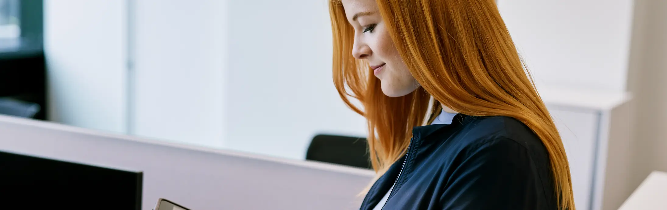 Eine Frau, die im Büro den Bildschirm eines Tablets berührt