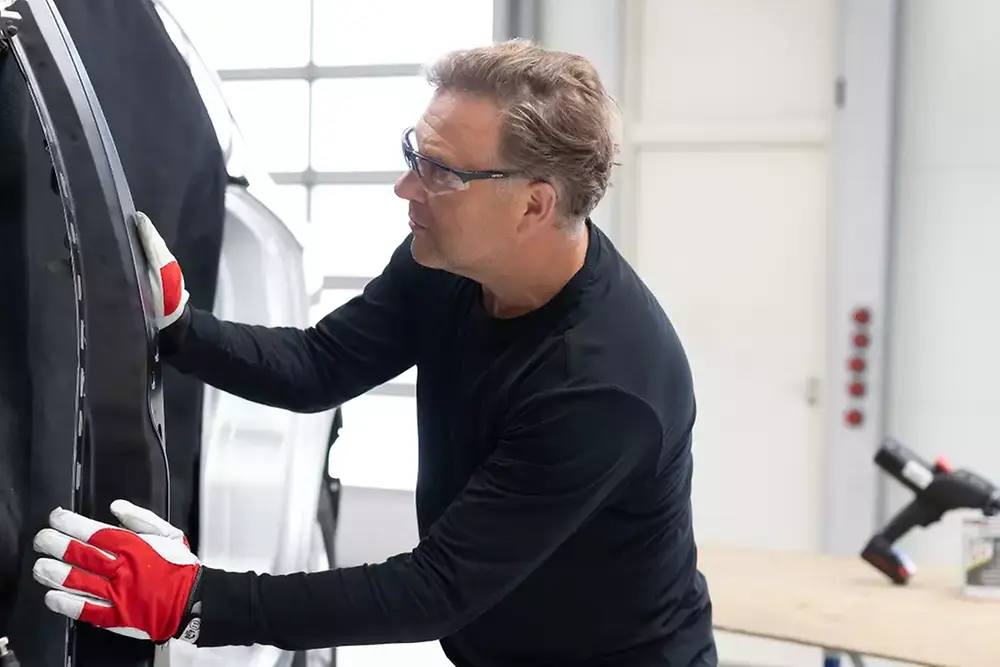 Ein Techniker repariert oder wartet eine Fahrzeugtür in einer Autowerkstatt.
