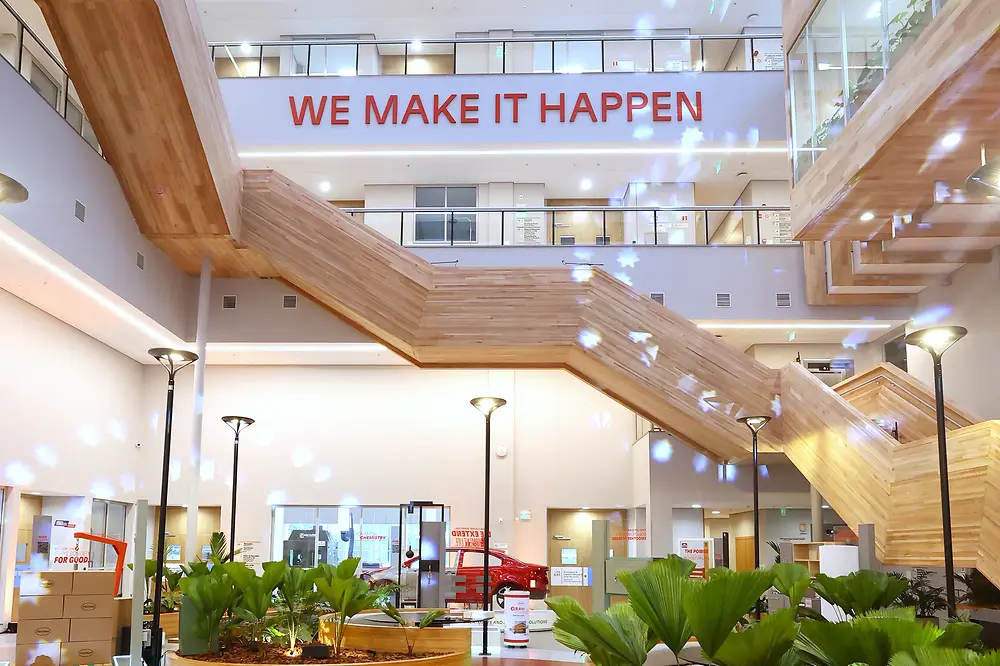 Modernes Atrium des Inspiration Centers Jundiaí mit Pflanzen und dem Schriftzug „WE MAKE IT HAPPEN“.