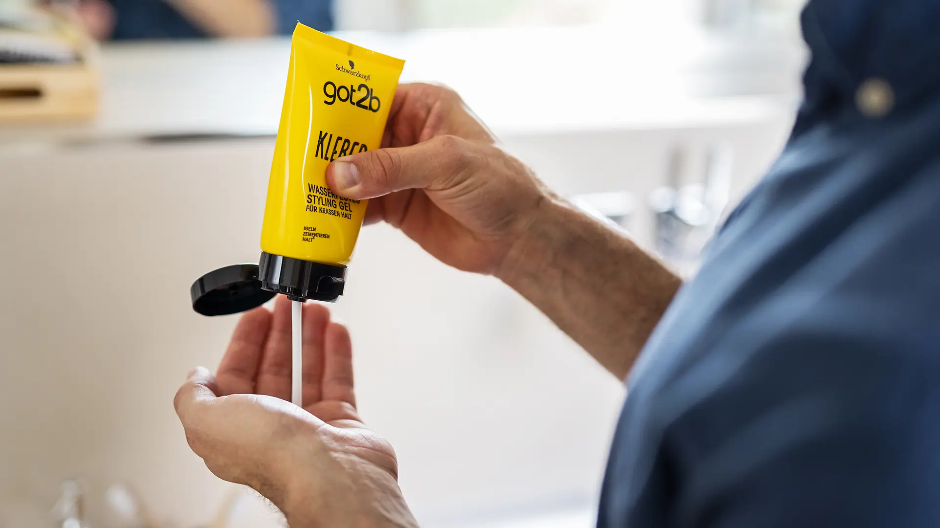 Person gibt got2b-Haarprodukt aus einer gelben Tube in die Handfläche.