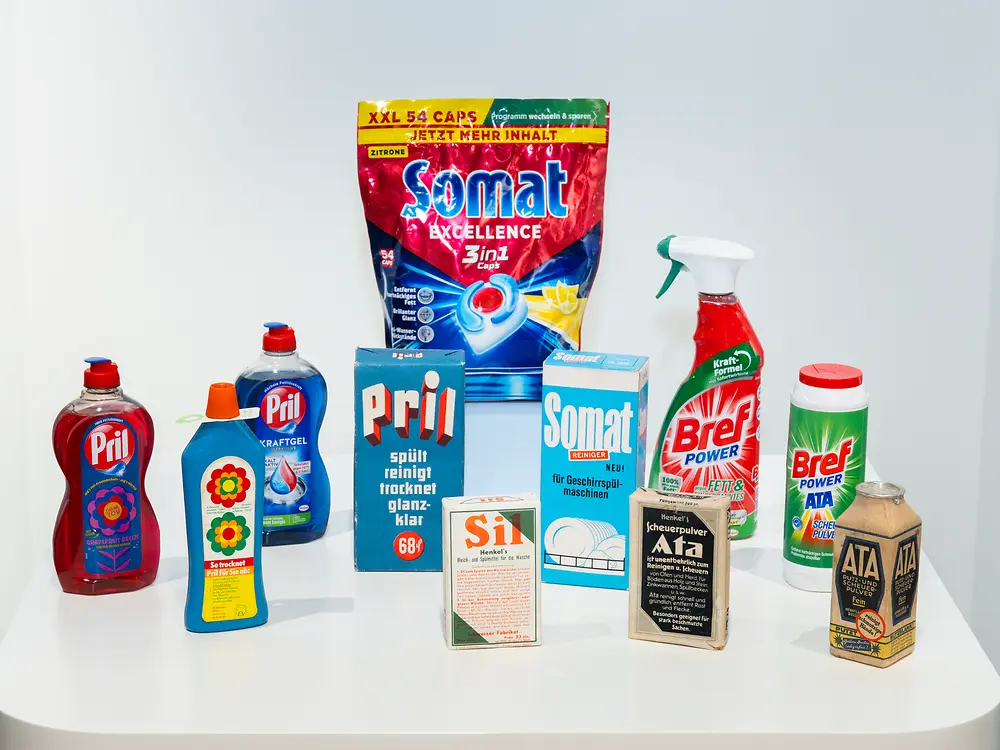 Historische und aktuelle Haushaltspflegeprodukte von Henkel, darunter Pril, Somat, Bref, Ata und Sil, nebeneinander präsentiert.